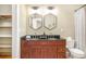 Bathroom featuring double sinks, hexagon mirrors, and wood vanity with black granite countertop at 3042 N Franklin St, Denver, CO 80205