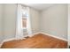 An empty bedroom featuring hardwood floors, a window with white curtains, and a neutral color scheme at 3042 N Franklin St, Denver, CO 80205