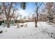 Snowy backyard featuring a fire pit with Adirondack chairs, storage, and a shed for outdoor enjoyment at 13438 W 23Rd Pl, Golden, CO 80401