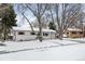 Charming single-story home with a white exterior, shutters, an attached garage, and a snow-covered front yard at 13438 W 23Rd Pl, Golden, CO 80401