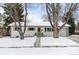 Charming single-story home featuring white paint, a gray door and shutters and a snow-covered front yard at 13438 W 23Rd Pl, Golden, CO 80401