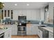 A bright and modern kitchen featuring stainless steel appliances, a gray backsplash, and white cabinets at 13438 W 23Rd Pl, Golden, CO 80401