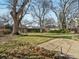Large, grassy backyard with mature trees, a stone path, and a wood fence at 2433 S Oneida St, Denver, CO 80224