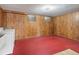 Unfinished basement features wood paneled walls, a red floor, and two small windows at 2433 S Oneida St, Denver, CO 80224