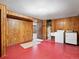Unfinished basement features wood paneled walls, a red floor, and laundry machines at 2433 S Oneida St, Denver, CO 80224
