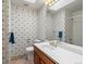 Well-lit bathroom with single sink vanity, floral wallpaper, and tiled shower at 2433 S Oneida St, Denver, CO 80224