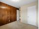 Bedroom showcasing wood-paneled accent wall, neutral carpet, and two doors at 2433 S Oneida St, Denver, CO 80224