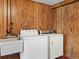 Laundry room features wood paneled walls, a utility sink and white washer and dryer at 2433 S Oneida St, Denver, CO 80224
