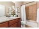 Bathroom with tile surround tub, neutral walls, white sink, and wood cabinets at 15122 Uinta St, Thornton, CO 80602