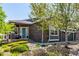 Beautiful gray home with a teal door, stone accents, a two-car garage, and lush, well-maintained landscaping at 15122 Uinta St, Thornton, CO 80602