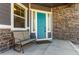 Inviting front porch with a teal door, stone accents, and a bench, perfect for relaxing outdoors at 15122 Uinta St, Thornton, CO 80602