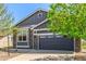 Exterior shot of a house with a gray two-car garage door, stone accents, and a well maintained lawn at 15122 Uinta St, Thornton, CO 80602