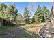 Spacious backyard featuring mature trees and a stone-lined flowerbed at 6991 S Lee Way, Littleton, CO 80127