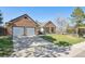 View of a brick home with a well-manicured lawn and a two-car garage at 6991 S Lee Way, Littleton, CO 80127