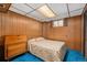 Bedroom with wood paneling, window with shutters, and a comfortable bed at 10596 Ura Ln, Northglenn, CO 80234