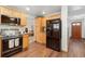 Efficient kitchen with wood cabinets, black appliances with view to the living room at 10596 Ura Ln, Northglenn, CO 80234