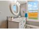 Bathroom featuring stylish vanity, round mirror, and a window with natural light at 3595 W 67Th S Ave, Denver, CO 80221