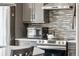 Stainless steel appliances accent the stylish kitchen with gray cabinetry and subway tile backsplash at 3595 W 67Th S Ave, Denver, CO 80221
