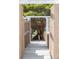 A tranquil walkway framed by textured adobe walls, a pergola, and a lush, mature tree at 3595 W 67Th S Ave, Denver, CO 80221