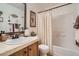 Well-maintained bathroom with wood vanity, shower over tub, and decorative mirror at 5843 Ceylon St, Denver, CO 80249