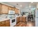 Well-lit kitchen featuring oak cabinets, marble countertops, and updated appliances with dining area view at 5843 Ceylon St, Denver, CO 80249