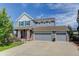 Charming two-story home featuring a three-car garage, inviting front porch, and manicured lawn on a sunny day at 4858 S Tibet St, Aurora, CO 80015
