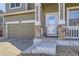 Close-up of the front entrance with stone pillars, a storm door, and a two-car garage at 1542 Cherry St, Brighton, CO 80601