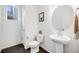 Powder room with stylish pedestal sink and a round mirror, complemented by a framed artwork and a view from the window at 16673 E Virginia Ave, Aurora, CO 80017