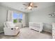 Charming Bedroom featuring a rocking chair and white crib, complemented by natural light from a large window at 16673 E Virginia Ave, Aurora, CO 80017