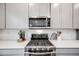 Modern kitchen with stainless steel appliances, white cabinetry, and tile backsplash at 16673 E Virginia Ave, Aurora, CO 80017