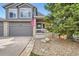 Front of home with well maintained landscaping, two car garage, brick accents, and an American flag at 6530 S Tabor St, Littleton, CO 80127