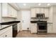 Well-lit kitchen featuring stainless appliances, white cabinets, and granite counters, creating a functional space at 7333 S Dexter Way, Centennial, CO 80122