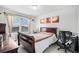 Cozy bedroom with wood-frame bed, neutral walls, a large window, and a dedicated workspace at 25064 E Archer Pl, Aurora, CO 80018