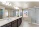 The primary bathroom features double sinks, a large mirror, and a glass walk-in shower at 19131 E 65Th Ave, Denver, CO 80249