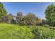 Spacious back yard with green grass, mature trees, and a fenced garden area at 5480 S Holly St, Greenwood Village, CO 80111