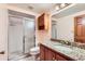 Cozy bathroom featuring a granite countertop, wood cabinets, and glass-enclosed shower at 5480 S Holly St, Greenwood Village, CO 80111