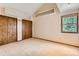 Carpeted bedroom featuring vaulted ceilings, closet storage and a window with tree views at 5480 S Holly St, Greenwood Village, CO 80111