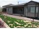 Back exterior view of home showcasing patio area, gray siding, and manicured lawn at 4580 S Ukraine Cir, Aurora, CO 80015