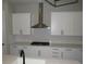 Close-up view of kitchen, featuring white cabinetry and stainless steel vent at 4580 S Ukraine Cir, Aurora, CO 80015