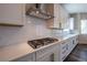 Close-up of the kitchen with white cabinets, stainless steel range hood, and subway tile backsplash at 4580 S Ukraine Cir, Aurora, CO 80015