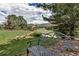 Backyard view showing a decorative metal bench, grass, rock landscaping and golf course views at 6379 Spotted Fawn Run, Littleton, CO 80125