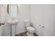 Powder room featuring sleek pedestal sink, modern toilet and decorative round mirror at 24707 E 40Th Ave, Aurora, CO 80019