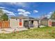 A cozy backyard with a covered patio, seating, a vibrant red door, and a well-manicured lawn at 2850 Roosevelt, Thornton, CO 80229