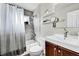 Updated bathroom with white tub, gray tiled shower, toilet, vanity and shelves at 2850 Roosevelt, Thornton, CO 80229