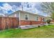 Side view of home featuring a brick foundation, tidy landscaping, and a wooden fence adding to the property's charm at 2850 Roosevelt, Thornton, CO 80229