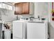 Basement laundry room features white washer and dryer, and overhead cabinets at 2850 Roosevelt, Thornton, CO 80229