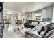 Bright living room with white floors, a dark leather sectional, and natural light from sheer-curtained windows at 2850 Roosevelt, Thornton, CO 80229