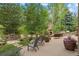Beautiful backyard patio featuring a stone fireplace, seating area, mature trees, and lush landscaping at 19061 Eagle Ridge Dr, Golden, CO 80401