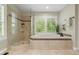 Bright bathroom with a soaking tub, a walk-in shower, and white shutters on the large picture window at 19061 Eagle Ridge Dr, Golden, CO 80401