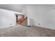 An open living area features neutral carpet, bright white walls, and wooden stairs leading up at 7507 Halleys Dr, Littleton, CO 80125